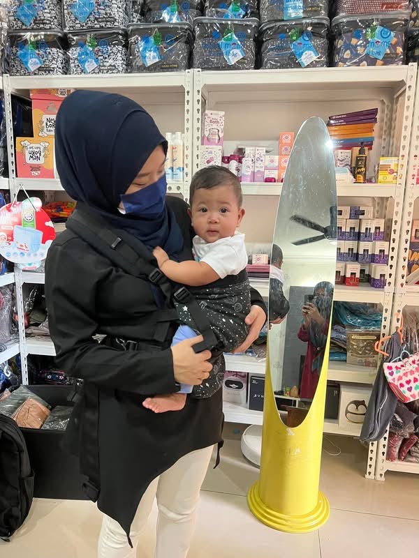 Ibu mencuba baby carrier bersama bayinya di kedai